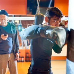 Selección de personas. Man boxing bag with trainer on workout